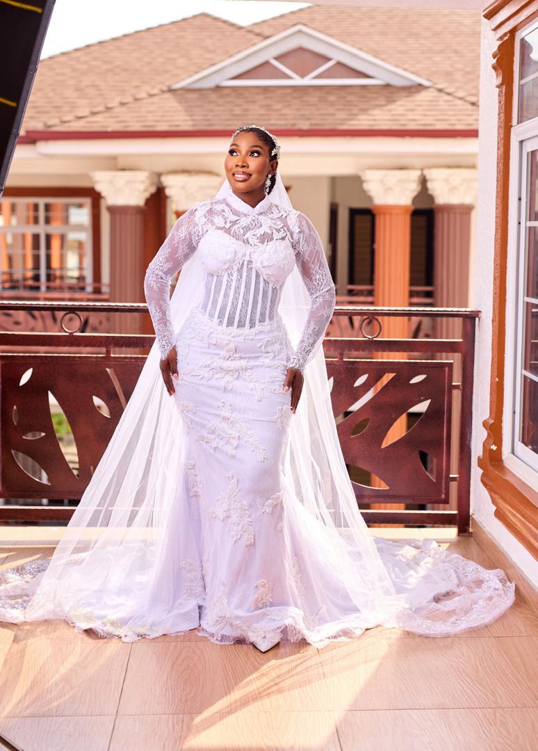 Full-length bride in lace mermaid gown on a sunlit balcony
